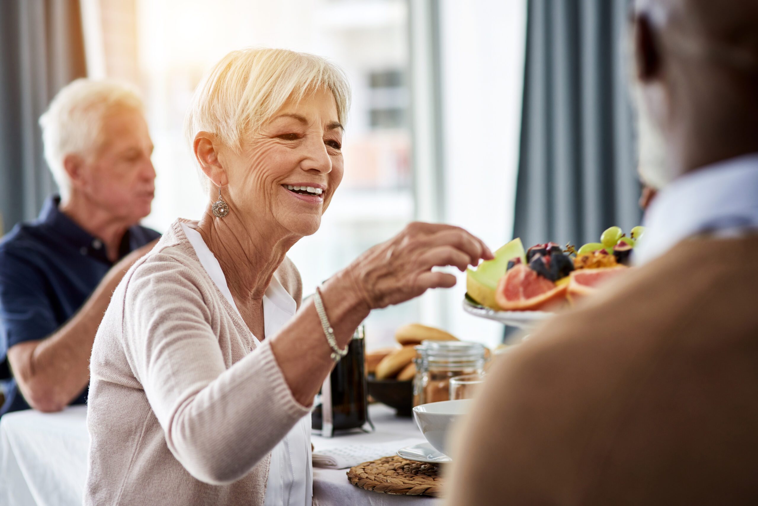 Older adults eating a breakfast with fresh fruit together.