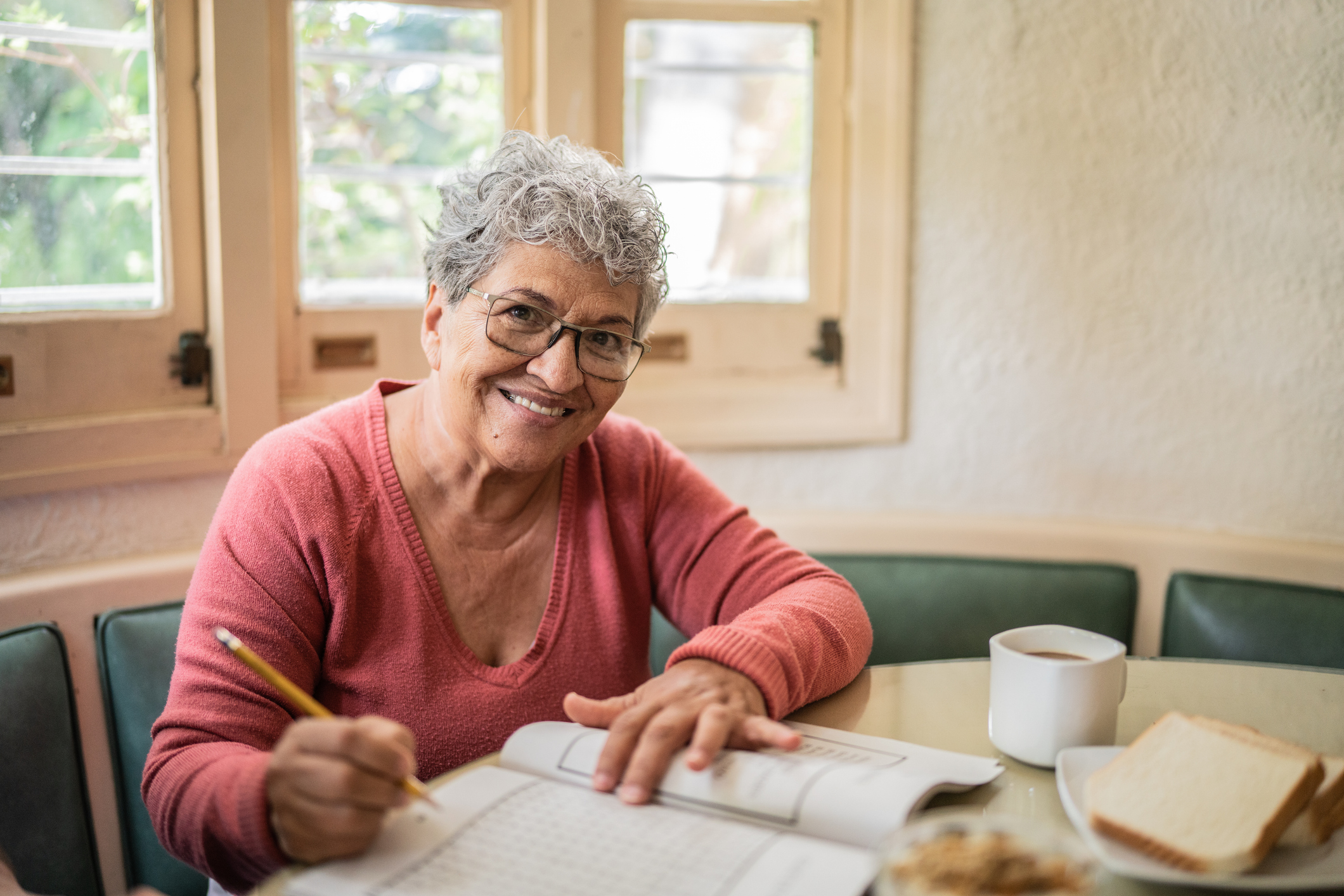 Portrait of a senior woman playing with crosswords at home Senior adult woman at table with pencil and paper