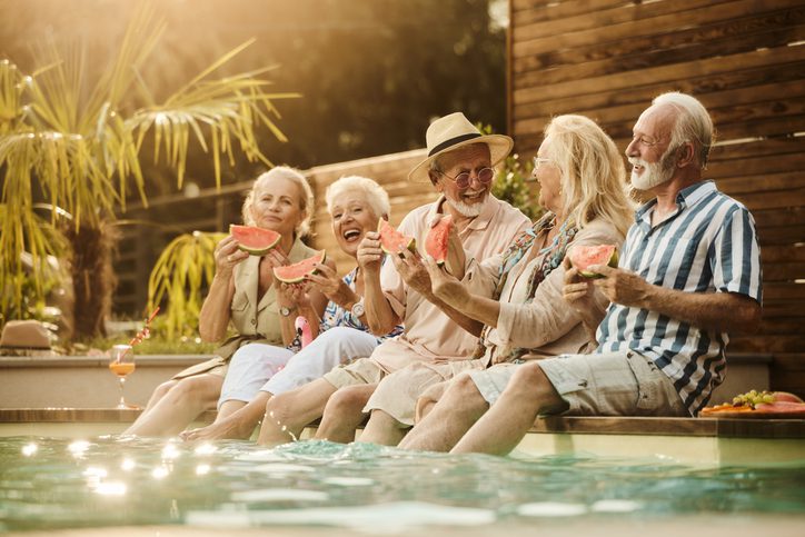 Group of senior adults by a pool eating watermelon