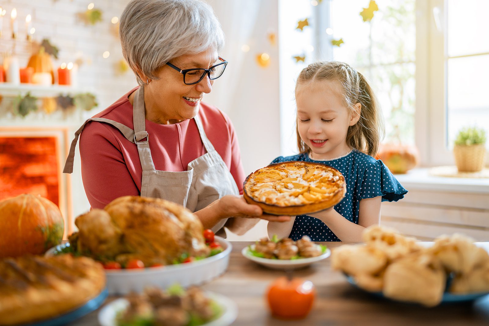 Happy Thanksgiving Day! Autumn feast. Family sitting at the tabl Older adult woman and her young granddaughter make a pie together to celebrate Thanksgiving