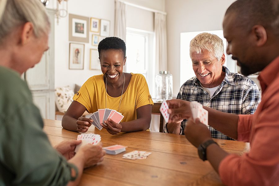 Being surrounded by neighbors is one of the benefits of senior living Two senior couples play a game of cards